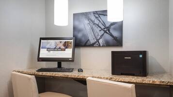 A workspace with a desktop computer, a monitor, a keyboard, a mouse, and two chairs.