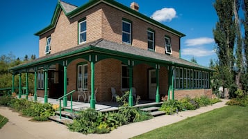 A two-story brick house with a green porch and a small garden.