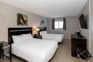 A hotel room with two beds, a desk, a chair, a TV, and artwork on the walls. - Coast Innisfail Hotel  (Innisfail)