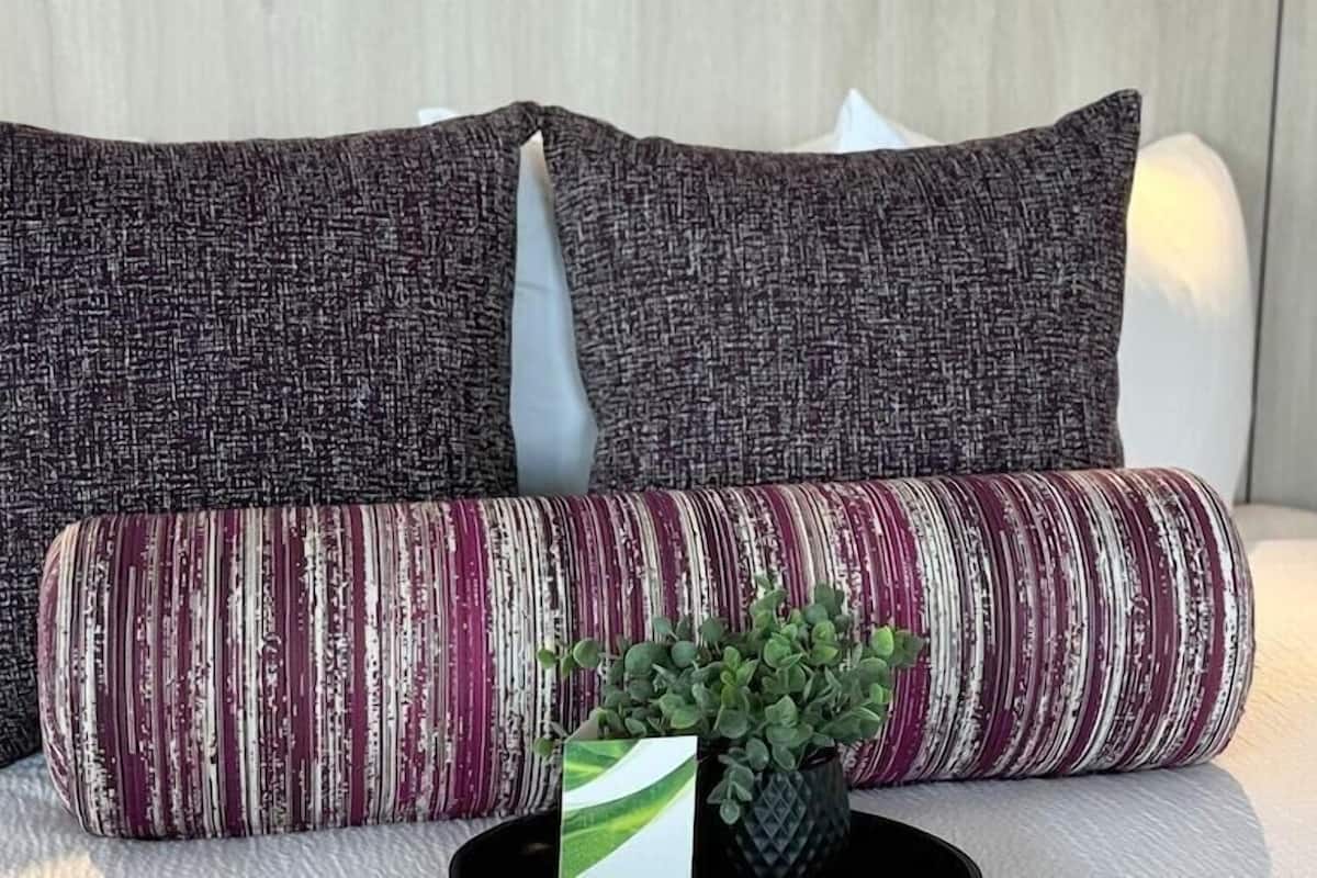 A bed with two pillows and a potted plant.