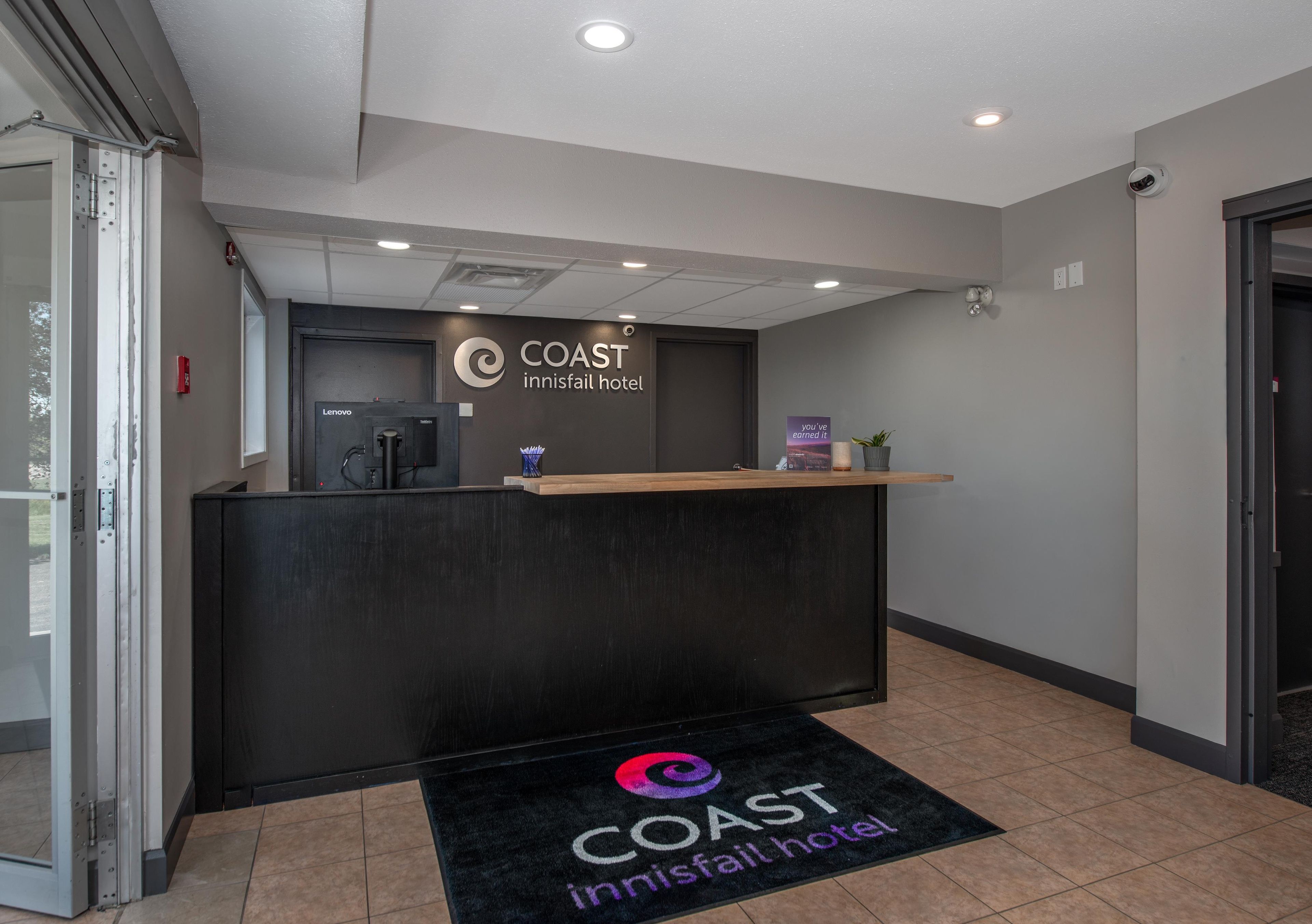 Mostrador de recepción del hotel COAST Innisfail con dispensador de agua, una planta pequeña y un cartel sobre el mostrador.