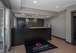 A reception desk at the COAST innisfail hotel with a water dispenser, a small plant, and a sign above the desk. - Coast Innisfail Hotel  (Innisfail)