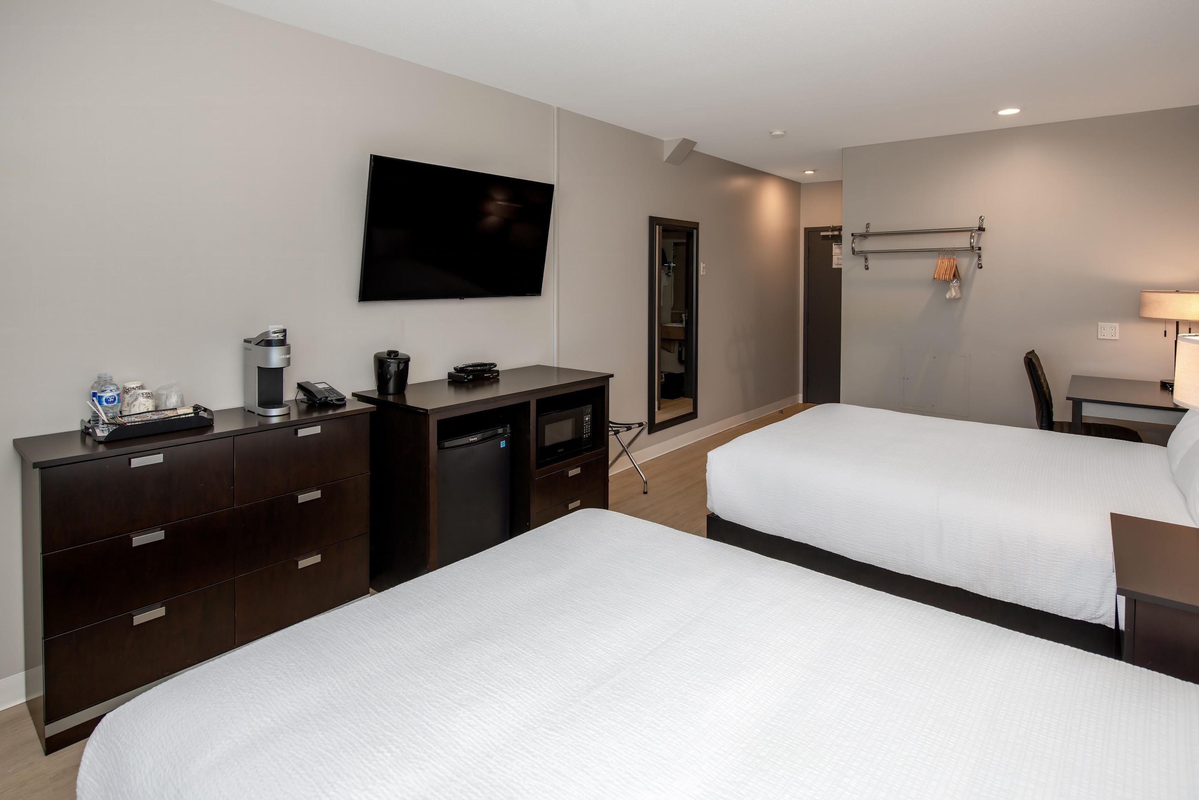 A hotel room with two beds, a TV, a desk, a chair, and a wardrobe.