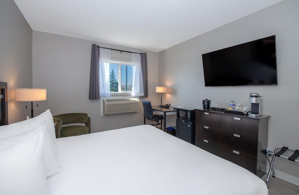 Habitación de hotel con cama, escritorio con silla, televisor y minibar.