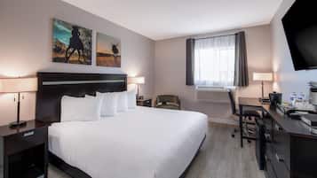 Una habitación de hotel con una cama grande, un escritorio, una silla, un televisor y obras de arte en las paredes.