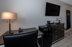 A hotel room with a desk, chair, lamp, flat-screen TV, minibar, and a coffee machine. - Coast Innisfail Hotel  (Innisfail)
