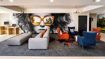 Un vestíbulo moderno con un mural grande, zona de estar y mostrador de recepción.