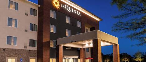 A hotel with a modern facade, a covered entrance, and a parking lot.