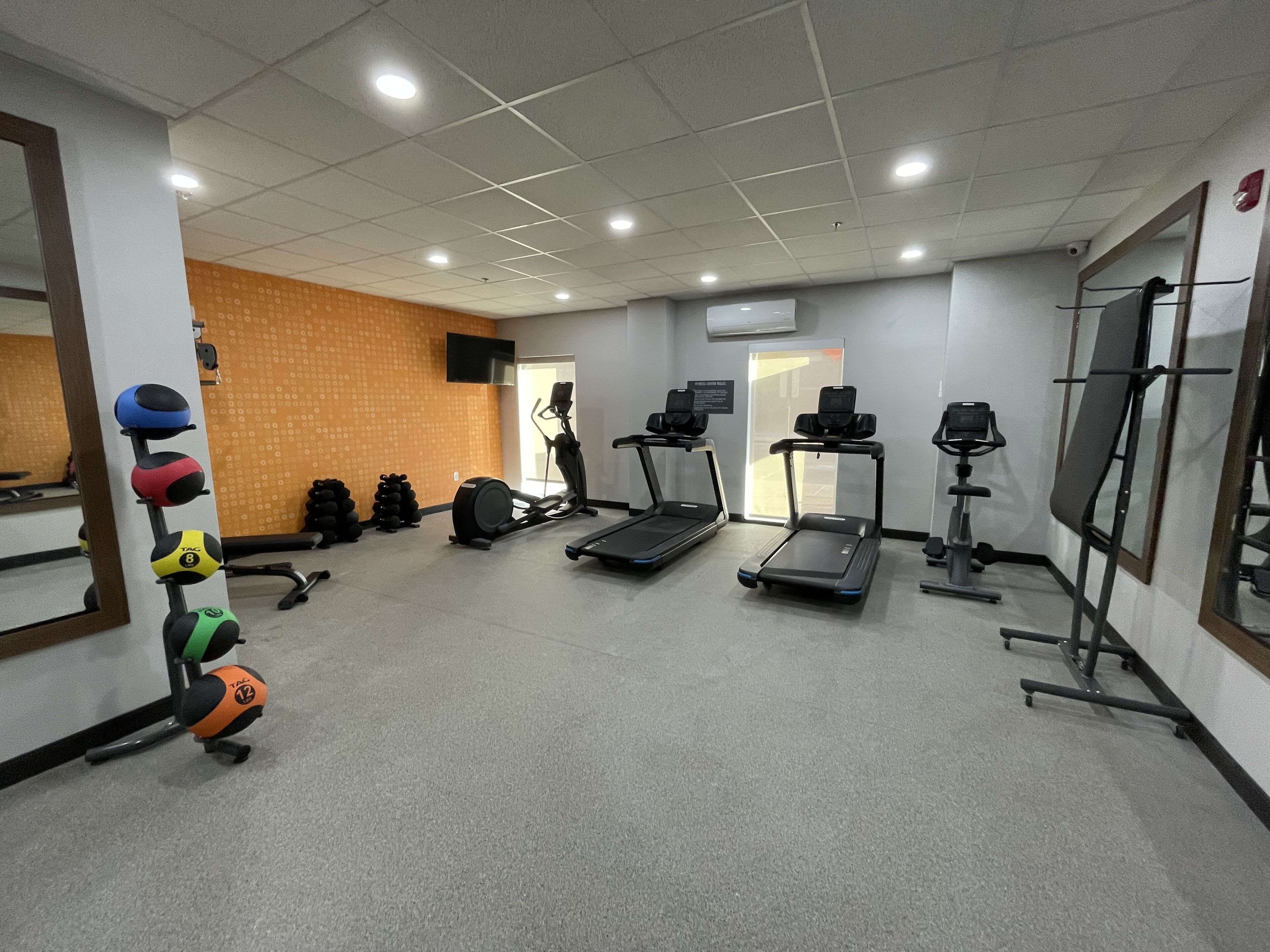 A gym with treadmills, exercise balls, and weights.
