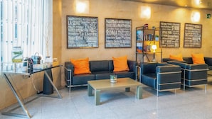 A modern lounge area with leather sofas, a coffee table, and a bookshelf.