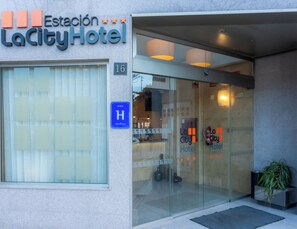 La Ciudad Hotel's entrance features a glass door and a clear view into the lobby area, with the hotel's name prominently displayed above.