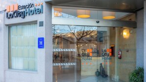 The entrance of LaCity Hotel with a glass facade, a visible fire extinguisher, and a blue handicap accessibility sign.