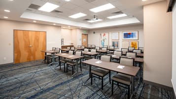 A conference room with multiple tables and chairs, a wooden door, and a carpeted floor.