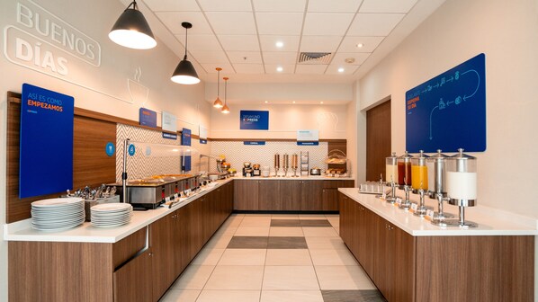 A breakfast buffet with various food stations, including cereal and pastries, and a sign indicating the start of breakfast. - Holiday Inn Express Hotel & Suites Cd. Juarez - Las Misiones by IHG (Ciudad Juárez)
