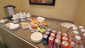 A buffet setup with various food items, disposable cups, and beverage cans.