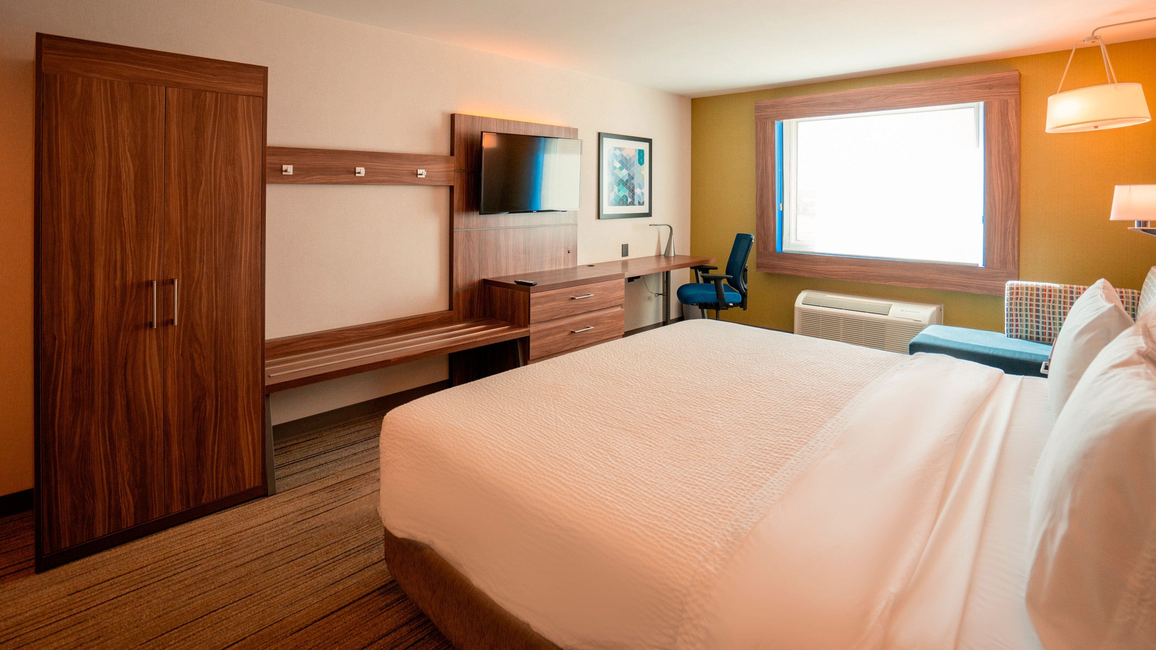 Una habitación de hotel con una cama grande, un escritorio con una silla, un televisor y una ventana con vistas.
