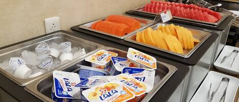 Un buffet proposant une variété d’aliments, notamment des yaourts, des fruits et des glaces.
