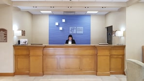 A reception desk with a Holiday Inn Express sign, a directory on the left, and a lamp on the right.