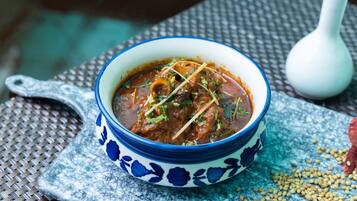Eine Schüssel Curry mit blauem Blumenmuster auf einer gewebten Matte mit verstreuten Samen.