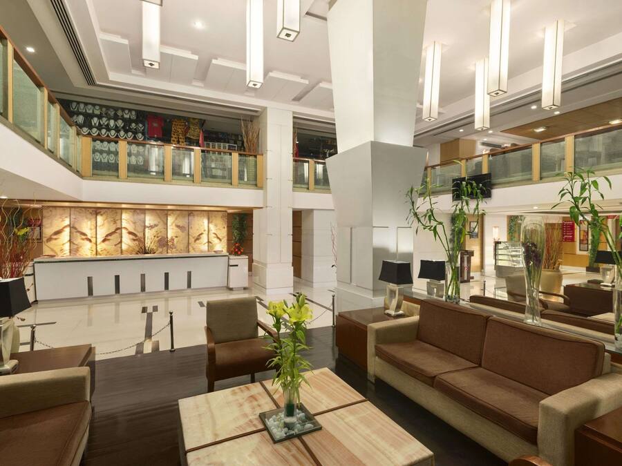 A spacious lobby with a high ceiling, modern furniture, and a central decorative wall.