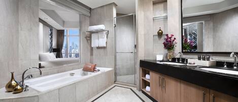 A modern bathroom with a large bathtub, a separate shower area, and a vanity with a sink and mirror.