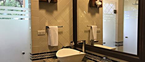 A bathroom with a large mirror, a sink with a vessel basin, and two towels on towel racks.