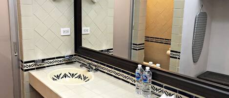 A bathroom with a sink, mirror, and towel racks.