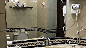 A bathroom with a sink, mirror, towel rack, toilet, and a phone on the wall.