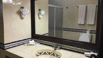 Un baño con un espejo grande, un lavabo con azulejos decorativos y toallas colgadas en la pared.