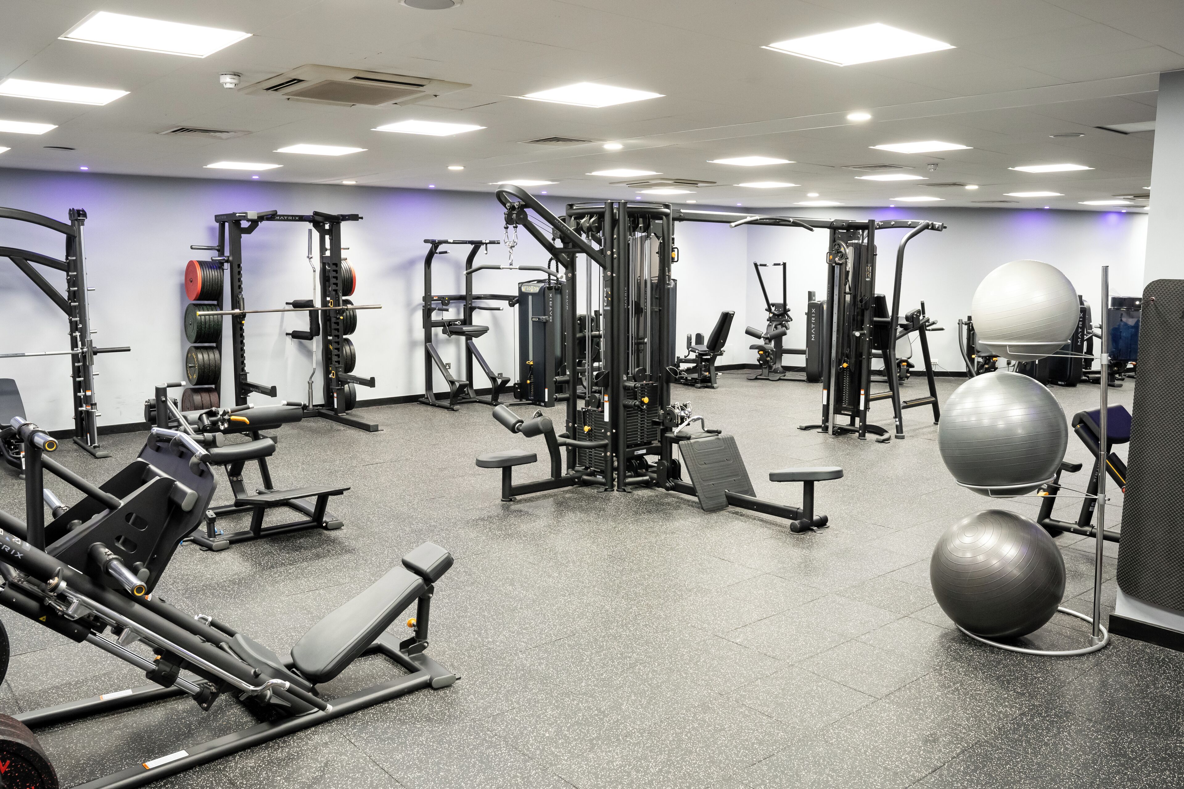 A gym with various exercise equipment, including weight machines, free weights, and exercise balls.