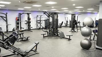 A gym with various exercise equipment, including weight machines, free weights, and exercise balls.