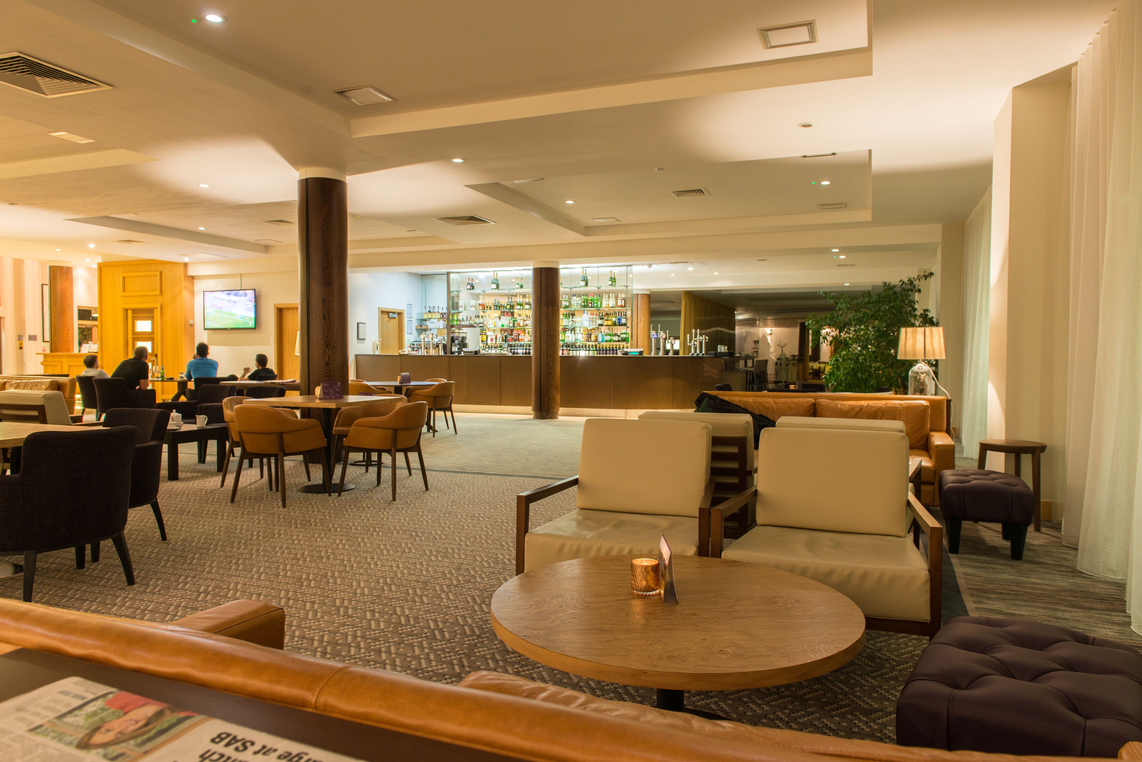 A spacious lobby with multiple seating areas, a bar, and a television screen.