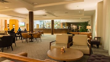 A spacious lobby with multiple seating areas, a bar, and a television screen.