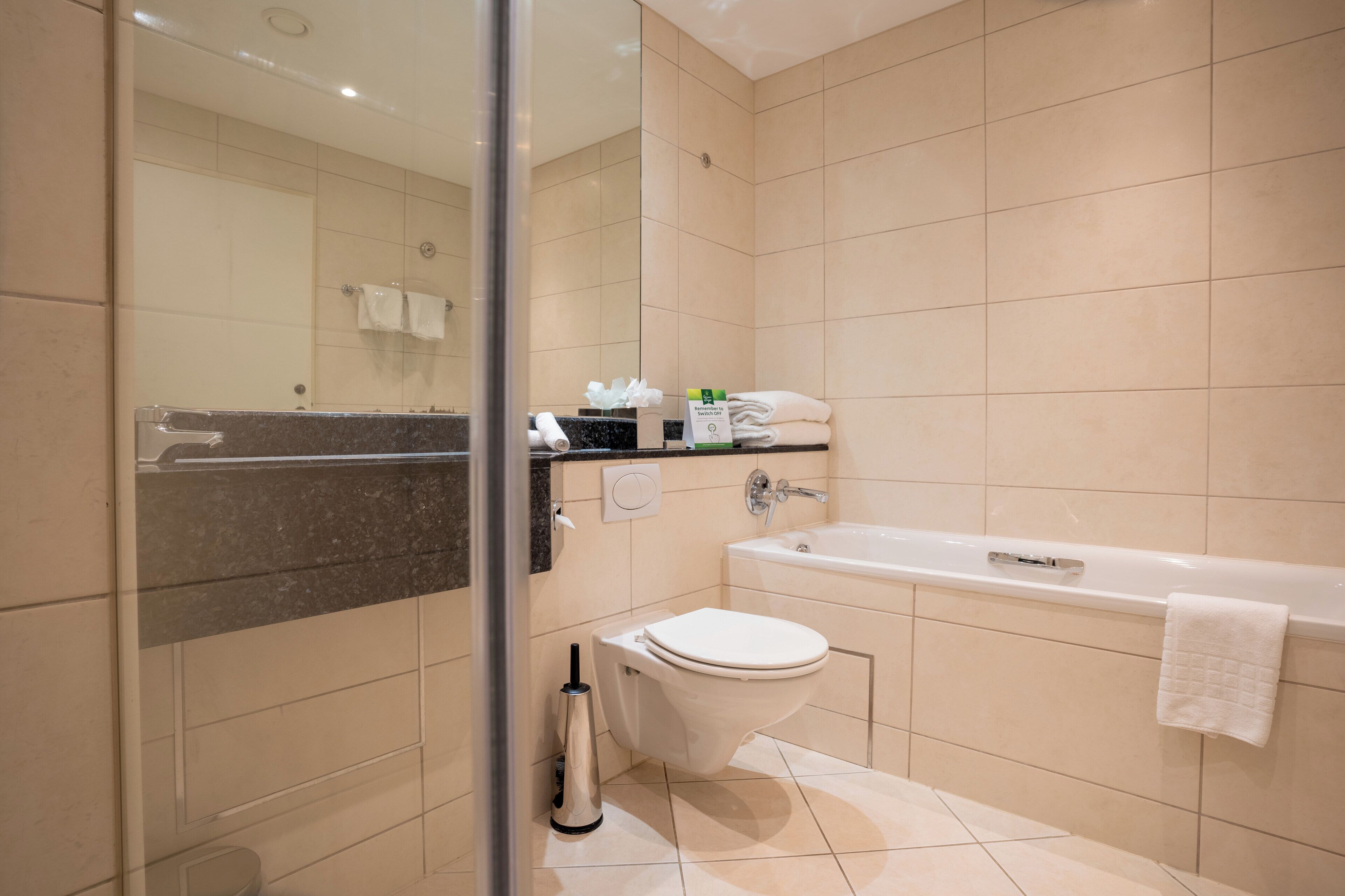 Un baño moderno con bañera, inodoro y cabina de ducha de cristal.