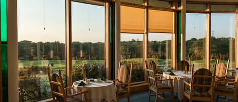 A dining area with large windows offering a view of a golf course.