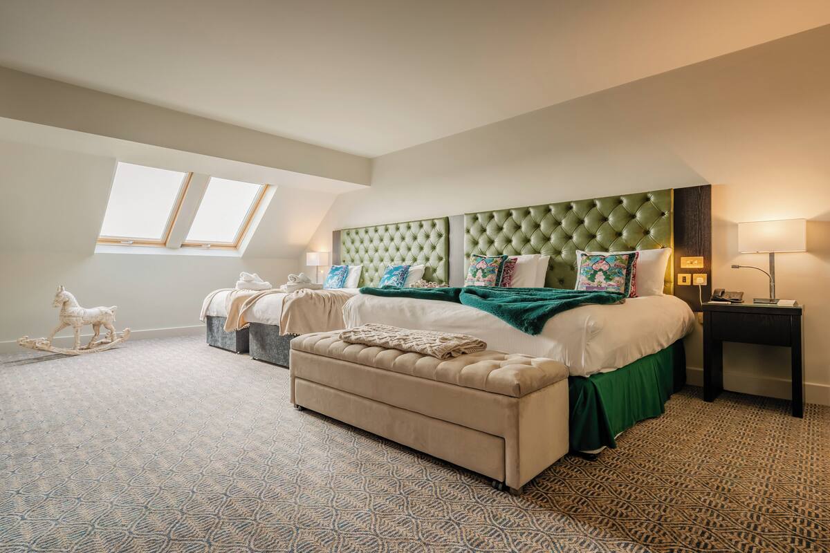 Un dormitorio con una cama grande, un sofá, una mesita de noche y una escultura decorativa de un caballo.