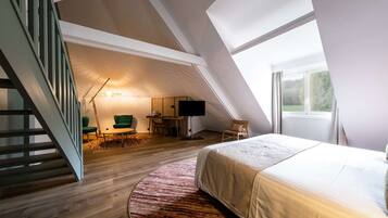 Een slaapkamer met een groot bed, een bureau, een stoel, een televisie en een trap.