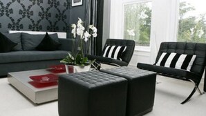 Un salon moderne avec un canapé gris, des fauteuils noirs et une table basse agrémentée de sets de table rouges et blancs.
