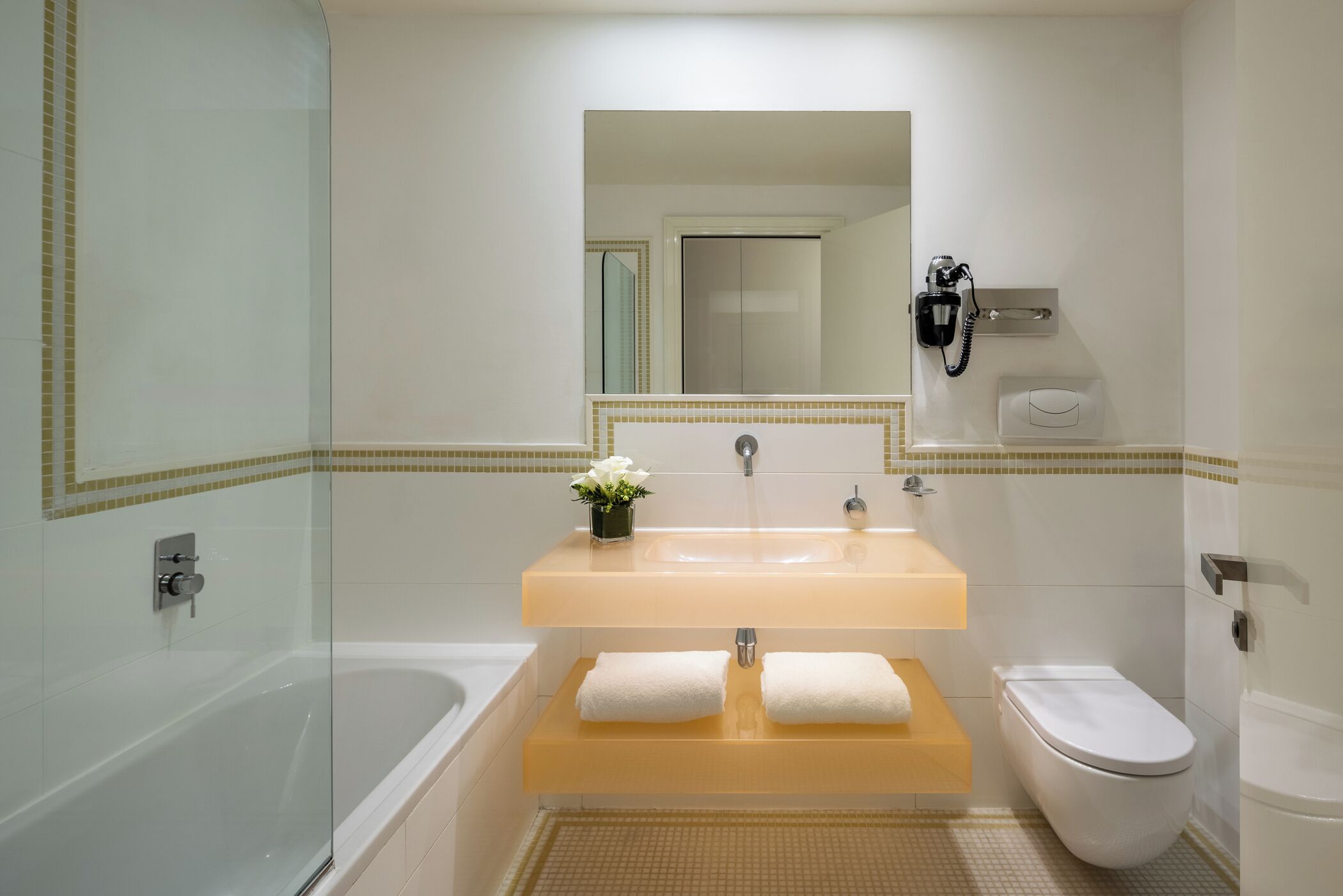 Une salle de bain avec une douche à parois de verre, une baignoire blanche, un lavabo avec un miroir au-dessus et des toilettes.