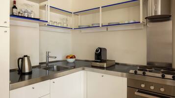 A modern kitchen with white cabinets, stainless steel appliances, and blue shelves.