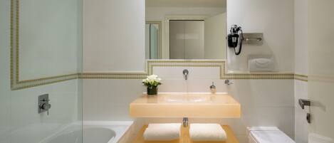 Une salle de bain moderne avec une douche à parois de verre, une baignoire blanche, un lavabo avec un miroir au-dessus et des toilettes.