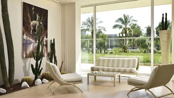 Un intérieur moderne avec une grande fenêtre, un jardin de cactus, un canapé à rayures et des fauteuils en osier.