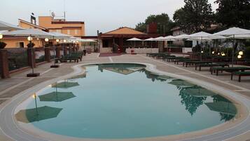 Una piscina circondata da aree relax, panchine e ombrelloni.