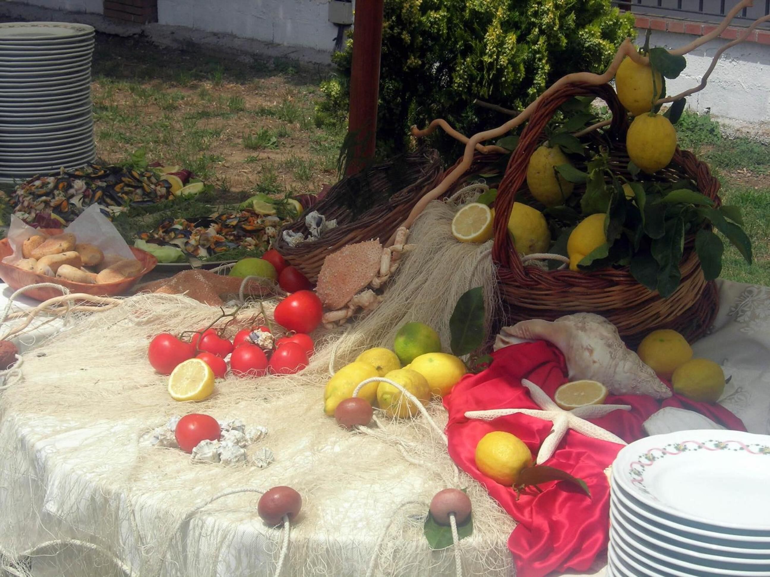 A table with various fruits and vegetables, including lemons, tomatoes, and a basket of lemons.