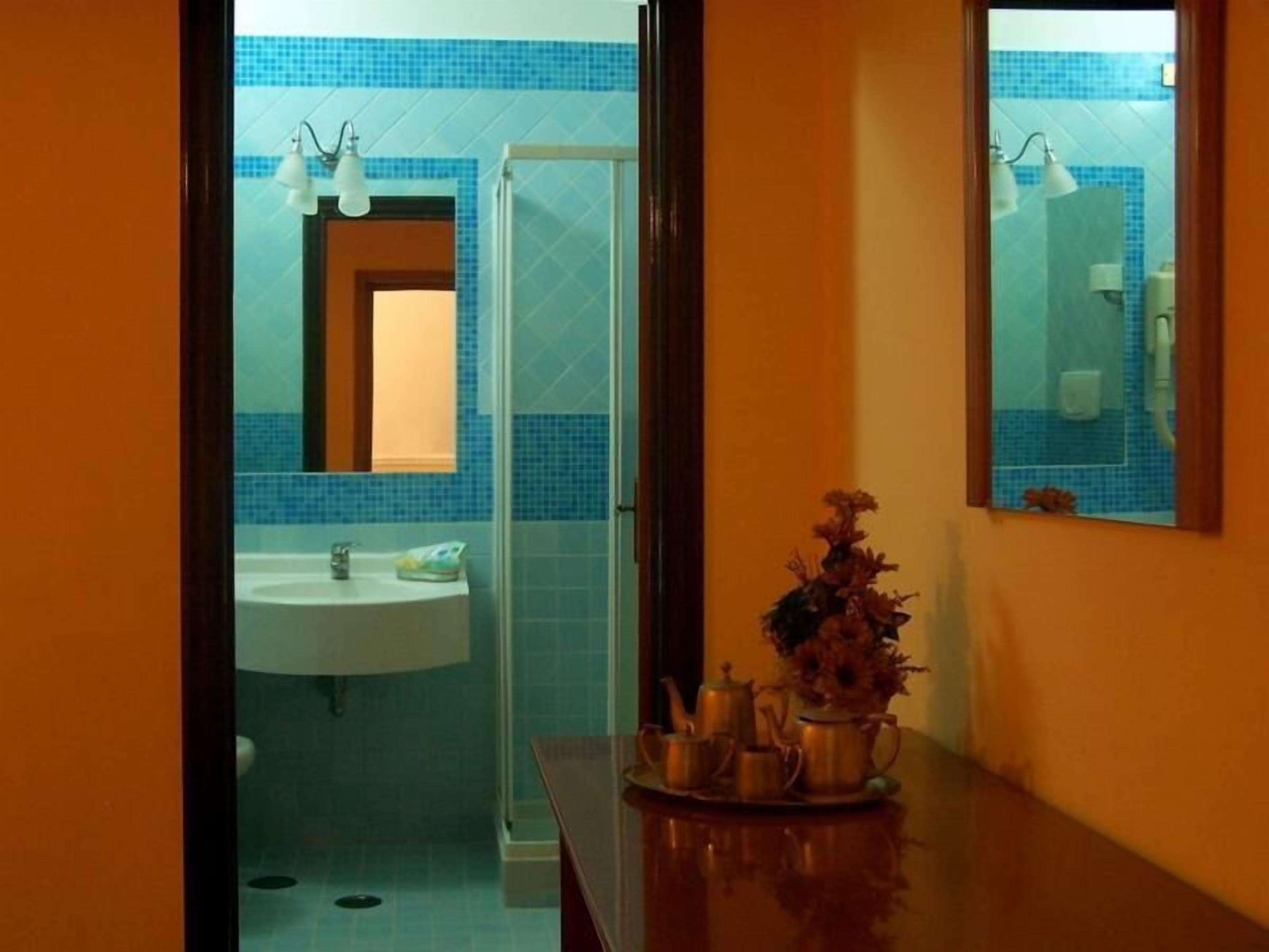 A bathroom with a sink, mirror, and shower.