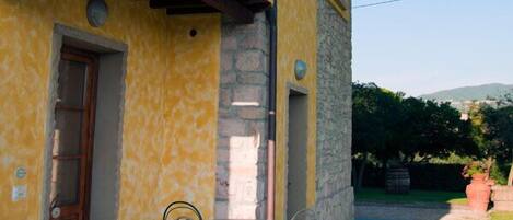 Un edificio amarillo con fachada de piedra, un balcón y un patio con mesa y sillas.