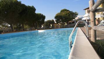 Una piscina al aire libre, sillones reclinables de piscina