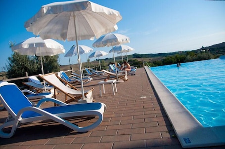 Una piscina al aire libre, sillones reclinables de piscina