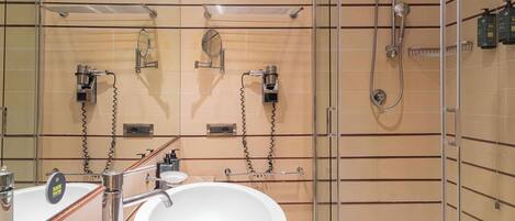 Ein modernes Badezimmer mit einem großen weißen Waschbecken, einer Duschkabine aus Glas und einem Spiegel mit der Aufschrift „Wassersparen“.