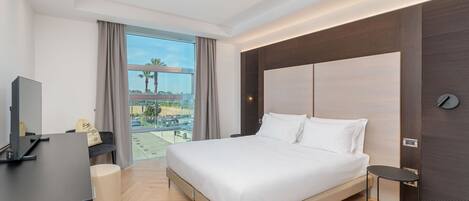 Habitación de hotel moderna con una cama grande, un escritorio y vista a un estacionamiento.